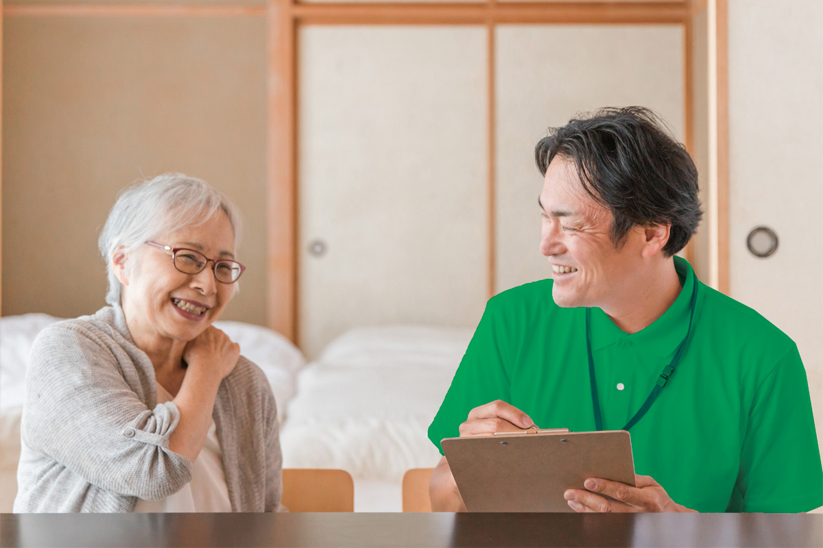 利用者さんのお宅を訪問し、笑顔で会話する職員と利用者さん