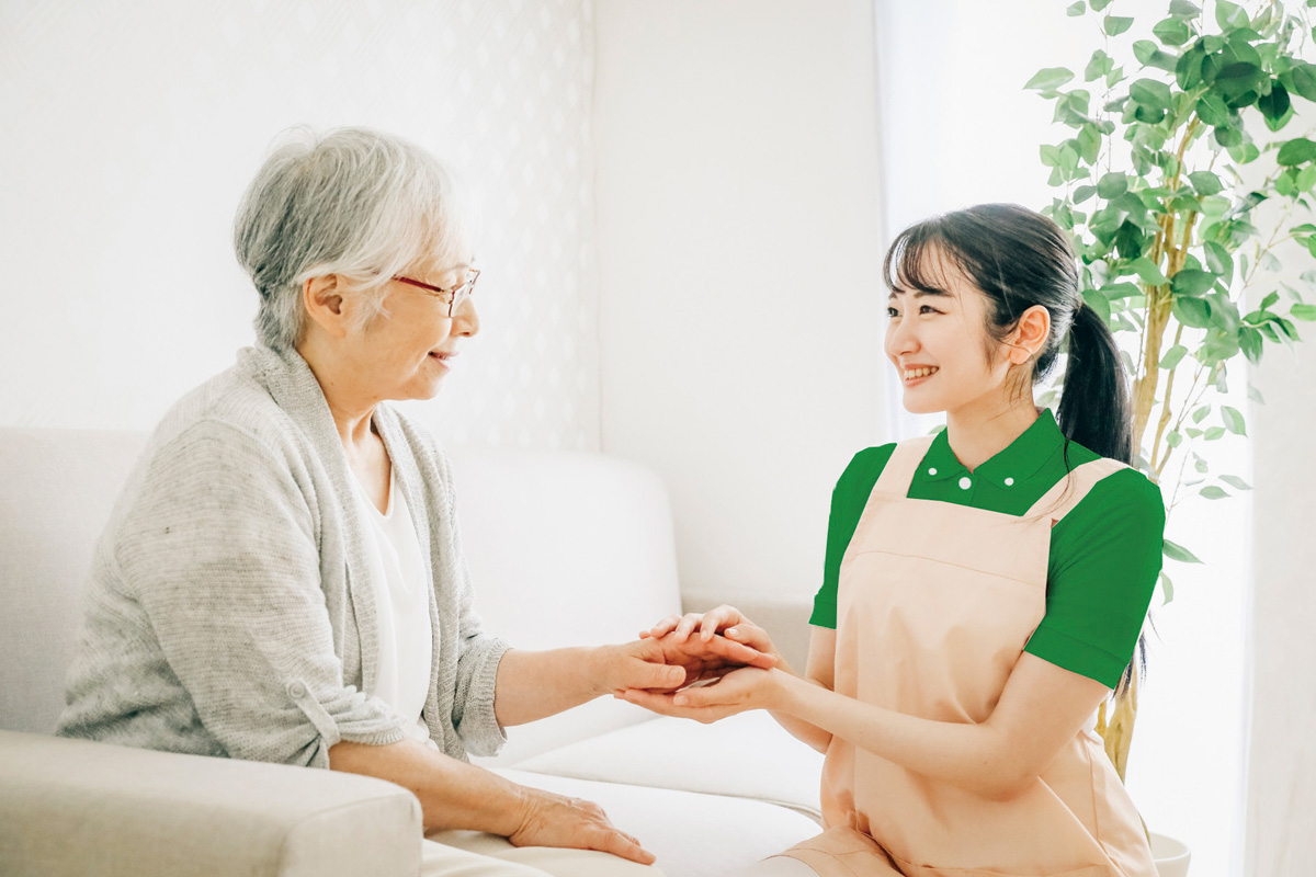 寄り添いながら利用者さんの手を握る職員の様子